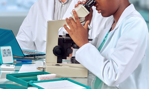 Close up image of a woman looking into a microscope