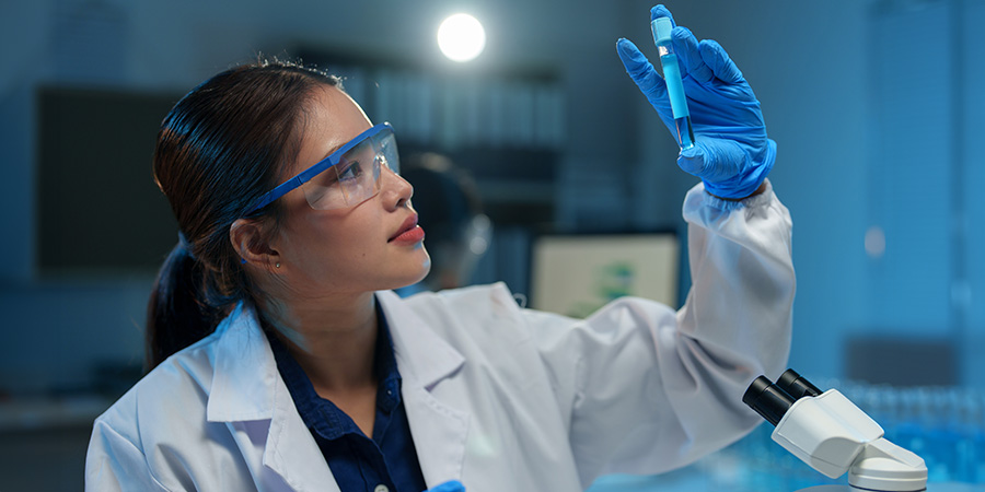 Asian female scientist holds a test tube filled with blue liquid in the laboratory